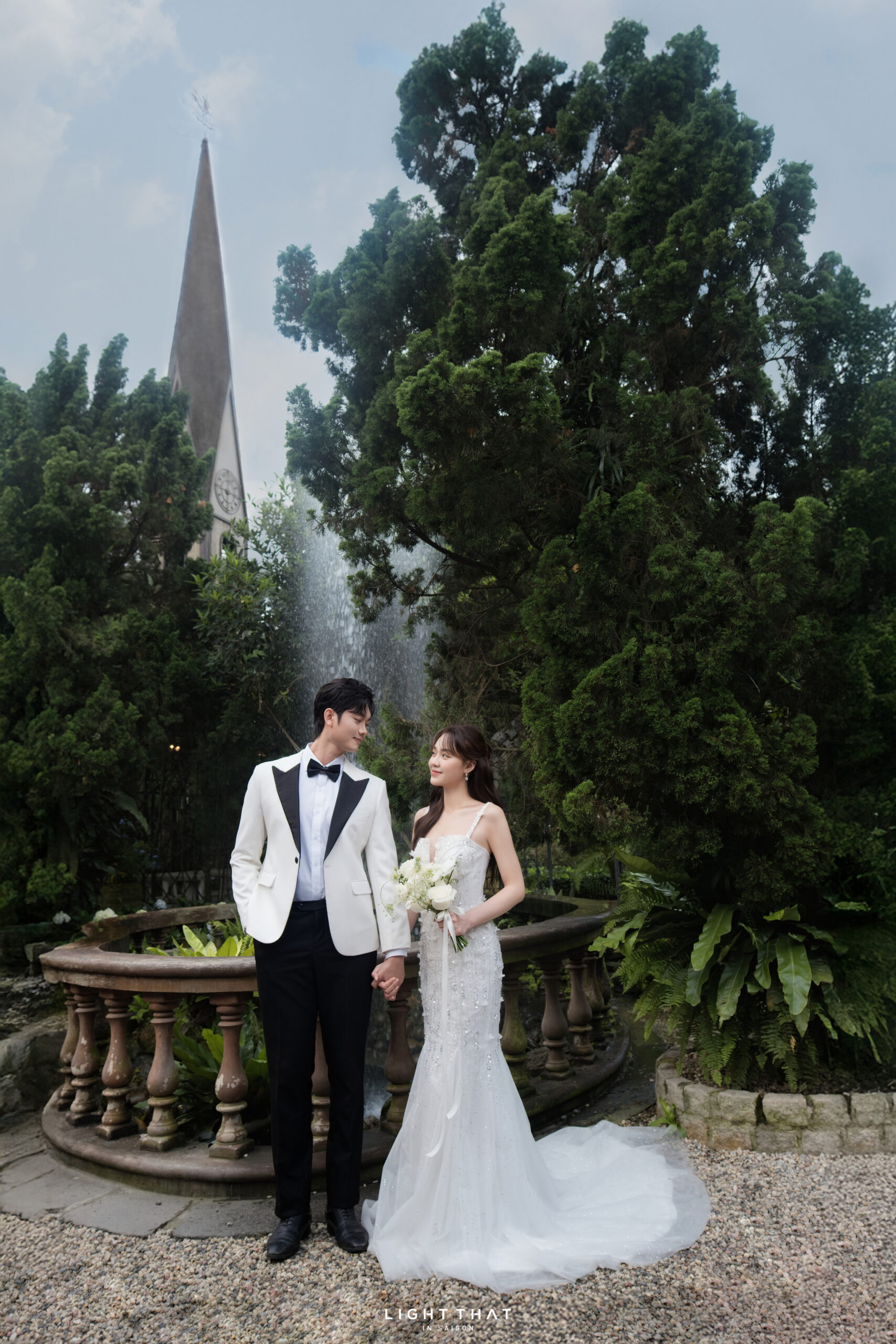 Cặp đôi chụp ảnh cưới tại phim trường Vũ Garden với khung cảnh cây xanh và hồ nước