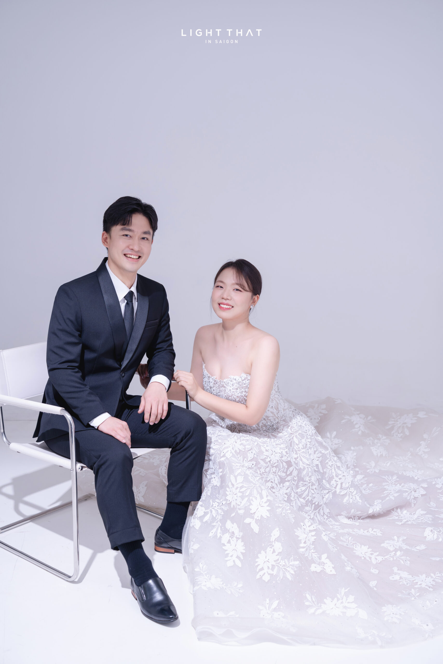 Tư thế ngồi nhẹ nhàng giúp cặp đôi tạo dáng chụp ảnh cưới phông trơn đẹp tự nhiên